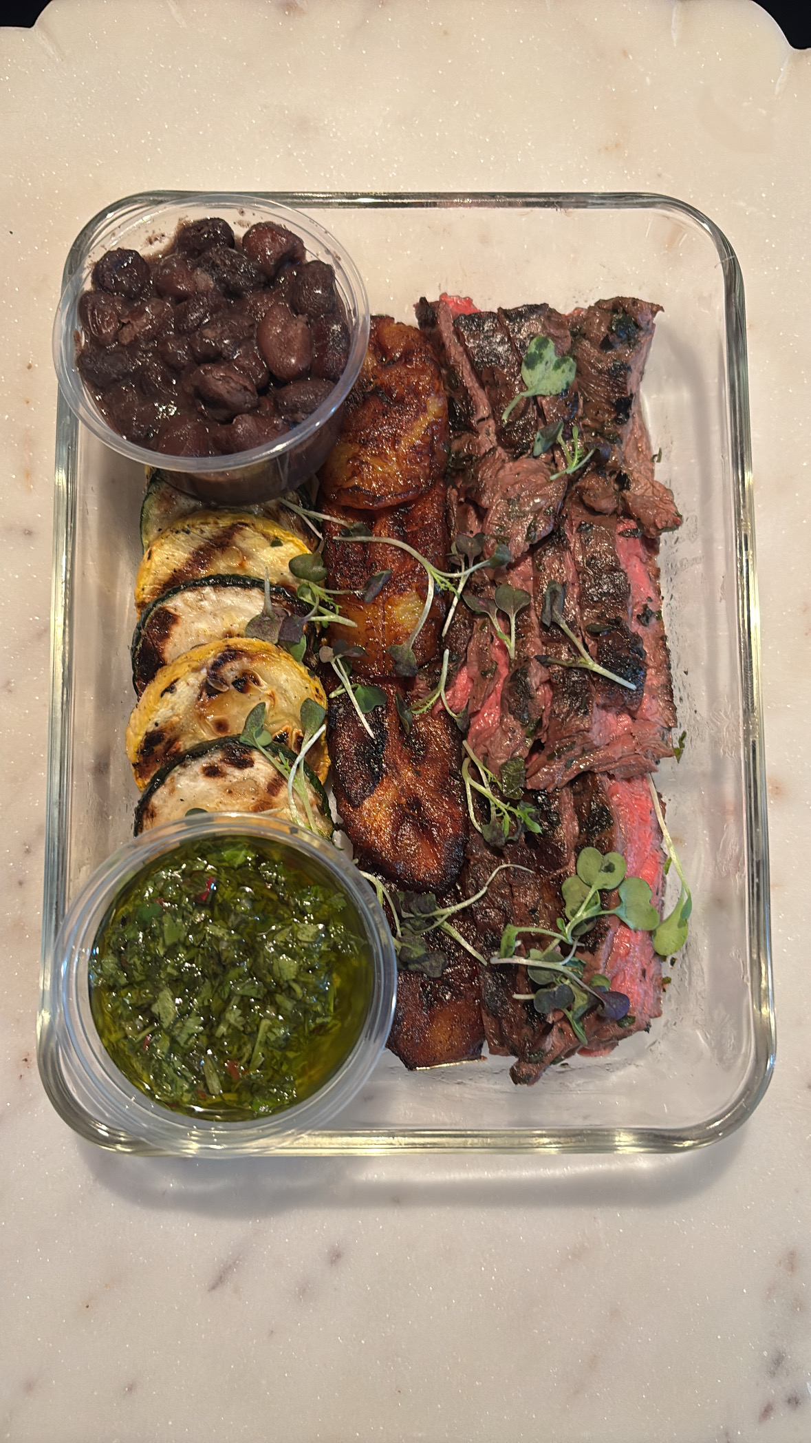 Chimichurri grass-fed skirt steak meal prep container with black beans, sweet plantains and grilled zucchini